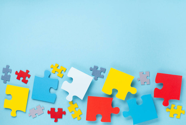 World Autism Awareness Day nebo měsíc koncept. Tvůrčí design pro 2. dubna. Barva puzzle, symbol povědomí o poruchách autismu spektra na modrém pozadí. Horní pohled, kopírovací prostor pro text.  - Fotografie, Obrázek