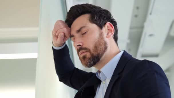 Werkproblemen. Een man zakenman leunt tegen de muur en houdt zijn hoofd, het voelen van sterke migraine hoofdpijn als gevolg van financiële problemen, verlies van een groot bedrag, en onrendabele investeringen. Hoofdpijn - Video