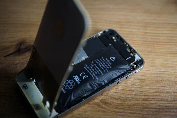 Kaunas, Lithuania - 2023 Marh 13: Iphone with exploded Lithium-ion battery. Li-ion swollen battery. High quality photo - Foto, Imagen