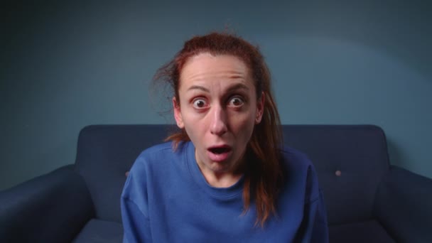 Shocked woman face with opened mouth and big eyes looking to camera on blue background. Portrait amazed girl and opened mouth in surprise. Facial people emotion. High quality 4k footage - Footage, Video