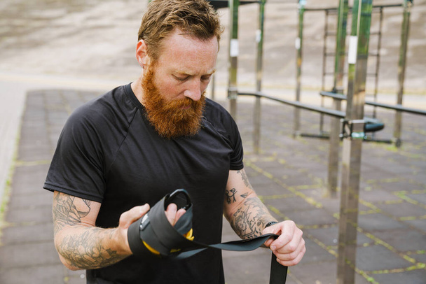 Ginger bearded sportsman standing on playground after workout outdoors - Foto, Bild