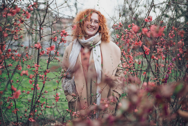 Portrait naturel d'une femme rousse caucasienne aux taches de rousseur et aux cheveux bouclés. Elle sourit et regarde ailleurs. - Photo, image