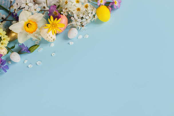Eleganti uova di Pasqua, fiori colorati e fiori di ciliegio su sfondo blu con spazio copia. Buona Pasqua! Modello di biglietto di auguri. Stendardo moderno di festa. Composizione festiva - Foto, immagini