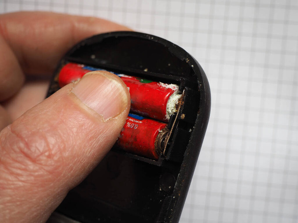 Person hält oxidierte Batterien in einem elektronischen Gerät.  - Foto, Bild