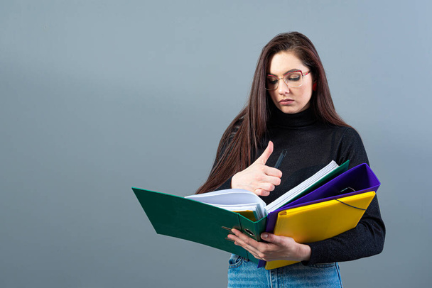 fashionable woman holding a colorfuls folders with documents, isolated on dark background - Photo, Image