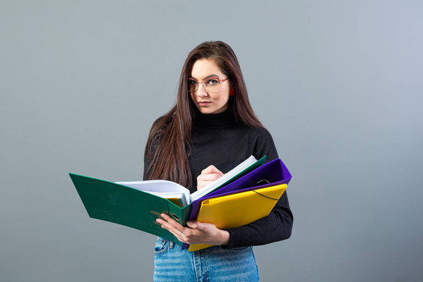 fashionable woman holding a colorfuls folders with documents, isolated on dark background - 写真・画像