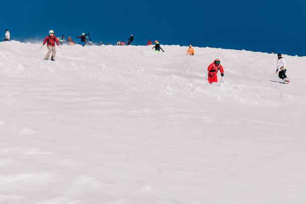 Karpaty, Ukraine, February 8, 2023. Skiers and snowboarders freeride in clear sunny weather on the slopes of the mountains near the resort of Dragobrat. High quality photo - Fotó, kép
