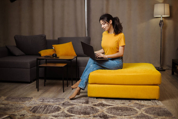 Feliz indio o árabe joven mujer independiente en el sofá y el uso de la computadora portátil. Trabajo remoto - Foto, imagen