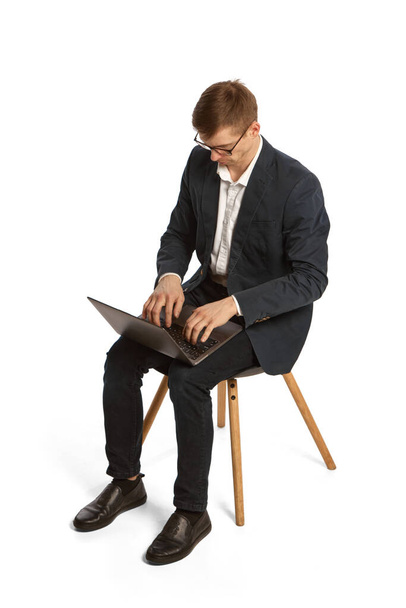 Portrait of young person, worker, student sitting and using laptop isolated over white background. Concept of business, career, finance, online app, ad. Studying and working, achievements - Fotó, kép