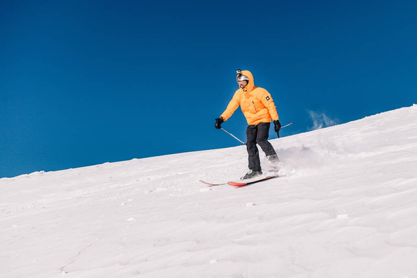 Karpaty, Ukraine, February 8, 2023. Skiers and snowboarders freeride in clear sunny weather on the slopes of the mountains near the resort of Dragobrat. High quality photo - Foto, Imagem