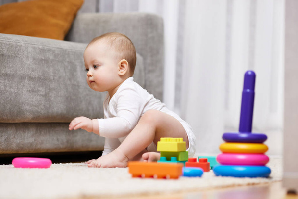 cute baby girl playing with toys on a carpet at home. Early development for kids. - Foto, Imagem