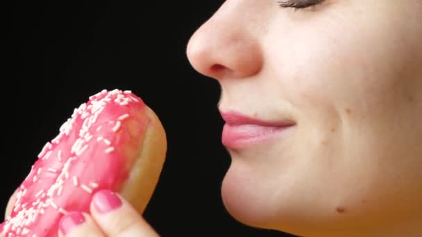 Een vrouw gaat een donut eten, ruiken en likken. De geur en smaak van voedsel, lekkernijen, veel calorieën. - Video