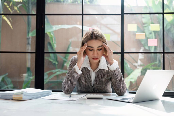 joven asiático mujer de negocios estrés pensamientos en trabajo o dolor de cabeza documentos en el escritorio en la oficina. - Foto, imagen