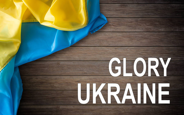 slogan Glorie aan Oekraïne in het Oekraïens op zwaaide nationale vlag. - Foto, afbeelding