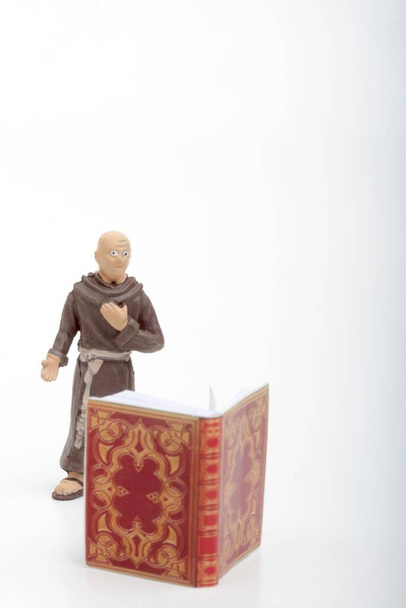figurine miniature d'un moine avec un grand livre ancien sur fond blanc - Photo, image