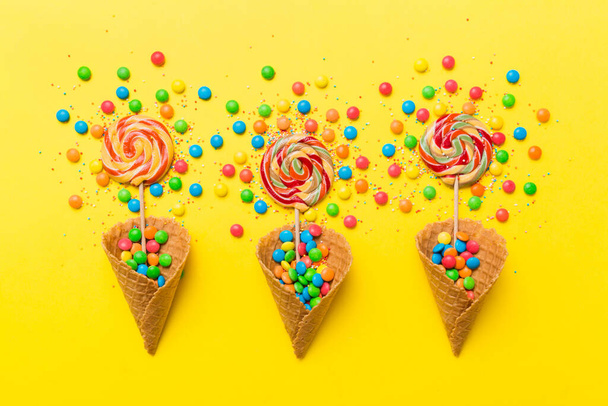 waffle cone full of assorted traditional candies falling out on colored background with copy space. Happy Holidays sale concept. - Foto, Imagem