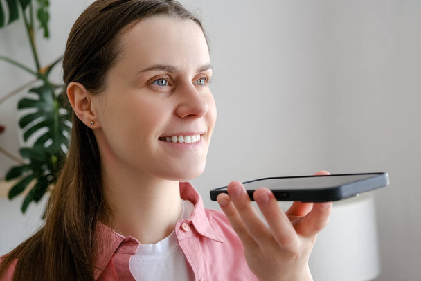 Easy mobile ai technology concept. Close up of smiling young woman holding phone speak activate virtual digital voice assistant on smartphone, happy girl ask internet assistance service make call - Valokuva, kuva