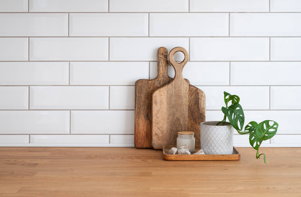 Accogliente cucina bianca con piano di lavoro in legno, fiori e taglieri in un interno minimalista su uno sfondo muro di mattoni bianchi. Copia spazio e vista frontale. - Foto, immagini