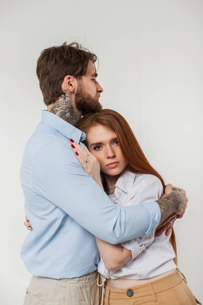 Beautiful fashion couple beauty redhead woman and handsome man in casual stylish elegant outfit hug on a white background in studio - Photo, Image