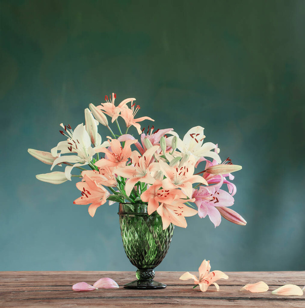 beautiful  lilies in glass green vase on dark background - Fotografie, Obrázek