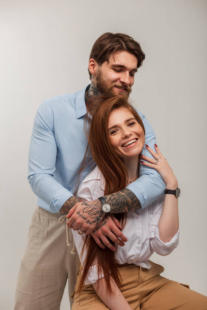 Módní krása mladý šťastný pár. Krásná zrzka žena a brutální hipster muž s tetováním a vousy - Fotografie, Obrázek