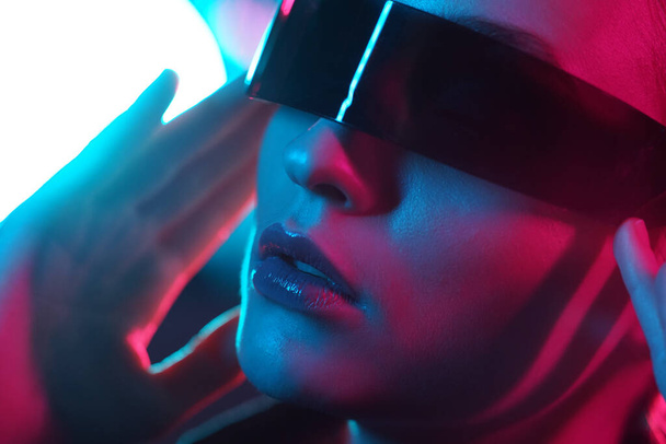 Portrait of a beautiful and young girl in cyberpunk style. Mixed color light effect. Futuristic concept with flares and lights. - Фото, изображение