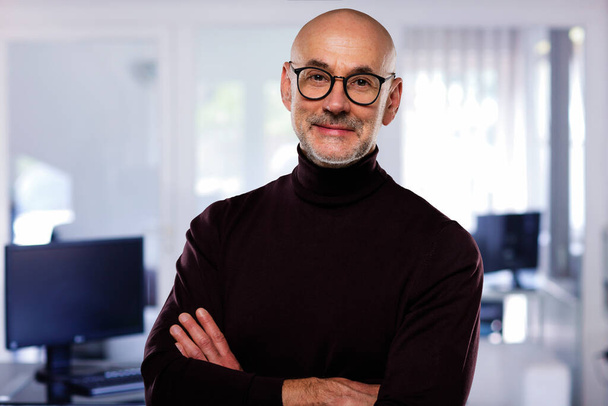Close-up of a confident man standing at isolated grey background. Smiling businessman wearing eyewear and turtleneck sweater. - Foto, immagini