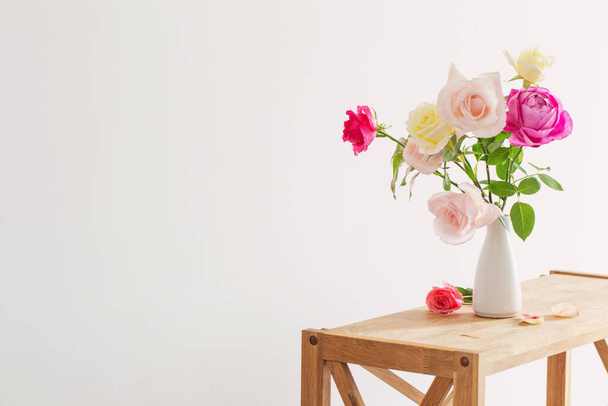 pink and white roses in white ceramic vase on white background - 写真・画像