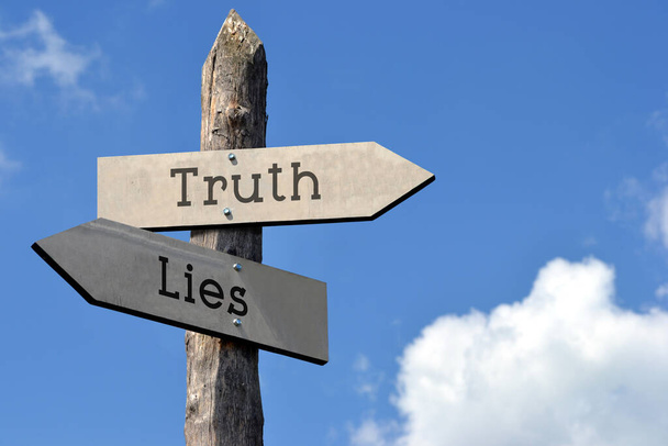 Verità e menzogne - cartello di legno con due frecce, cielo con nuvole - Foto, immagini