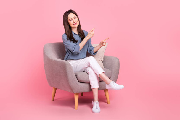 Full body photo of sitting office manager comfort armchair directing fingers empty space psychologist advert isolated on pink color background. - 写真・画像