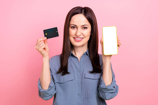 Photo of young promoter lady eshopping advert pay loan wireless plastic card no limits demonstrate phone screen isolated on pink color background. - Photo, image