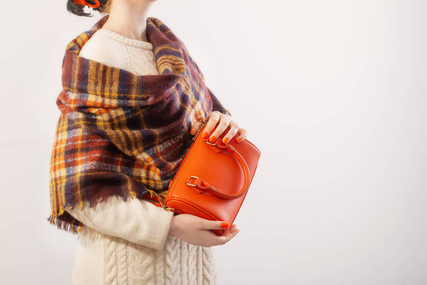 woman in knitted sweater with orange handbag on white background - Фото, изображение