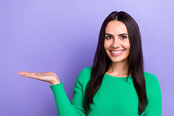 Photo of shiny cheerful lady dressed green sweater holding arm empty space isolated violet color background. - Фото, изображение