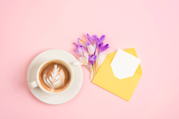 Šálek kávy, kytici jarních květin a obálku s prázdnou kartou. Top view, flat lay, mockup. - Fotografie, Obrázek