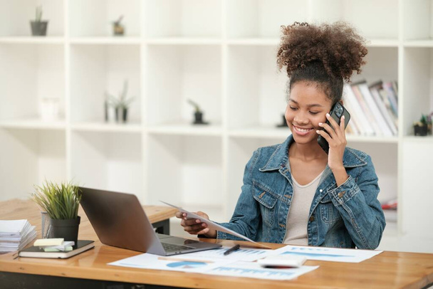 Femmes africaines intelligentes travaillant dans un beau bureau, travaillant sur ordinateur portable, utiliser le téléphone, parler sur le téléphone portable. . Photo de haute qualité - Photo, image