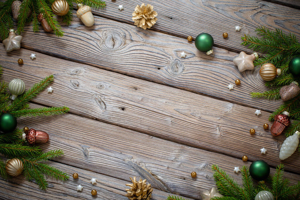 zlaté vánoční hračky s jedlovými větvemi na tmavém dřevěném pozadí - Fotografie, Obrázek