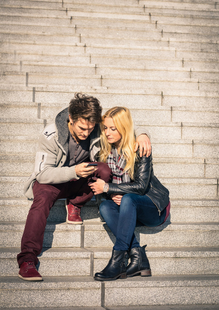 Hipster couple in love having fun with smartphone - Modern concept of connection in a relationship together with mobile phone technology - City urban lifestyle representing everyday life rapport - Foto, Imagem