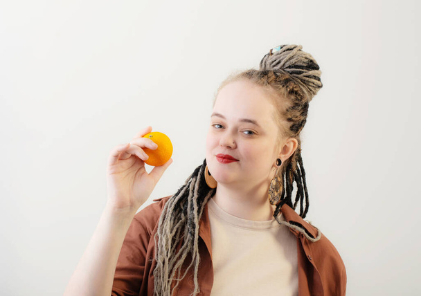 young woman with orange on white background - Zdjęcie, obraz