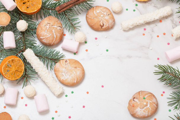 цукерки та печиво з гілками ялинки на білому мармуровому фоні
 - Фото, зображення