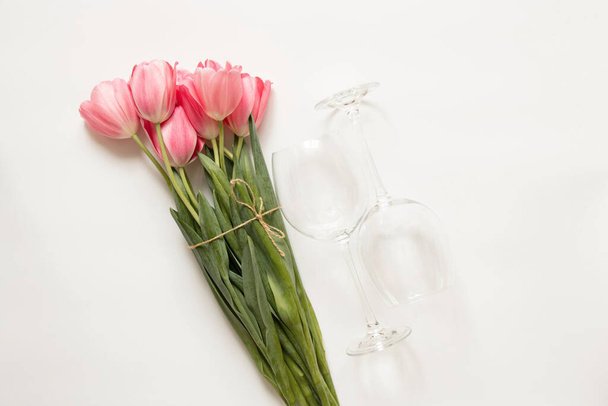 Růžové tulipány a dvě prázdné sklenice na bílém pozadí zblízka - Fotografie, Obrázek