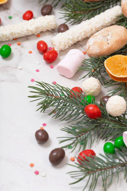 candies and cookies with christmas tree branches on white marble background - Photo, image