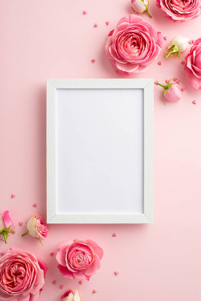 Women's Day concept. Top view vertical photo of photo frame pink peony roses and sprinkles on isolated pastel pink background with copyspace - Photo, Image