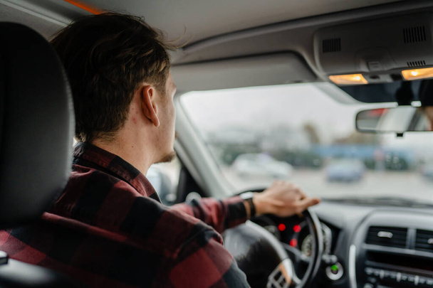 egy férfi fehér férfi barna hajjal és bajusszal ül egy autóban felnőtt vezető visel inget vezetés közben autós utazás koncepció valós emberek másolja tér vissza nézet - Fotó, kép