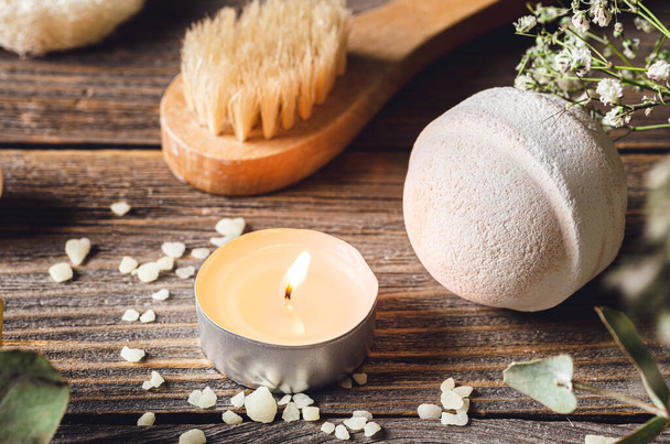 Spa composition with bath bomb, candle and dried flowers on a wooden surface. - Photo, Image
