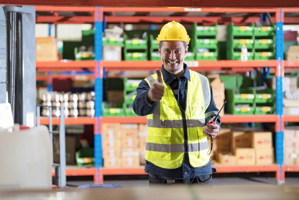 Male employee using a radio in the warehouse to inspect the product to meet the needs of customers. - Photo, Image
