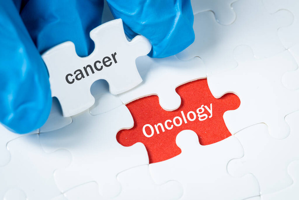 Cancro e oncologia, Concetto di salute, Puzzle con il testo Il cancro svela uno sfondo rosso con le parole Oncologia, Esami preventivi, diagnosi, Promozione della ricerca oncologica - Foto, immagini