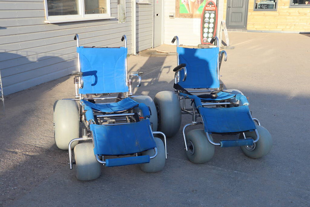 Strand rolstoelen op saunton strand voor ouderen te worden geduwd langs het zand, in het bijzonder een strand rolstoel met handgrepen en grote wielen, zodat ze kunnen rollen over het zand - Foto, afbeelding