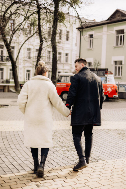Mladý zamilovaný pár se prochází po ulici a užívá si čerstvého vzduchu. Šťastný manželský pár. Stylový pár, muž a žena - Fotografie, Obrázek