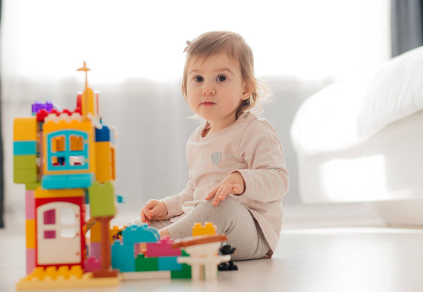 adorable child playing with multicolored building blocks on floor. - Foto, Bild