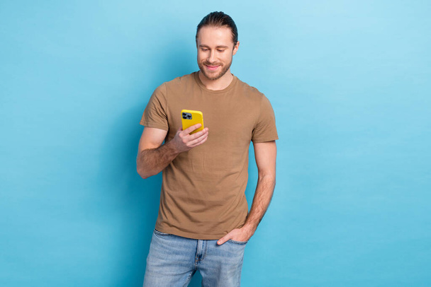 Portrait of positive attractive man hold use telephone chatting isolated on bright blue color background. - Fotó, kép